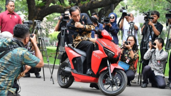 Jokowi sedang naik motor Gesits.