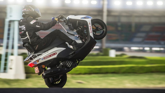 Aksi wheelie sepeda motor dengan skutik.