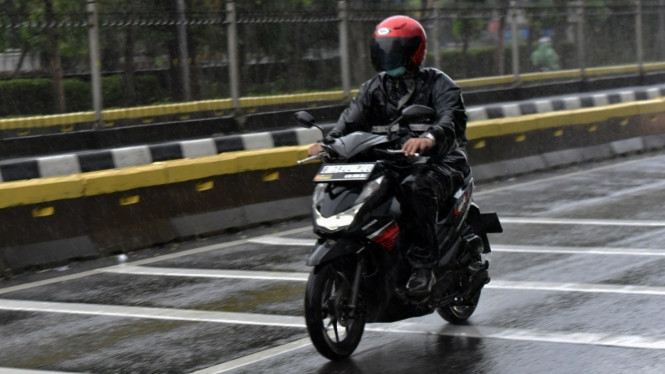 Pemotor memakai jas hujan