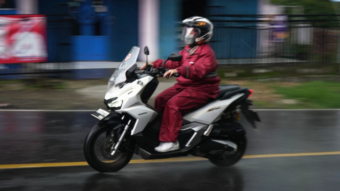 Pemotor memakai jas hujan