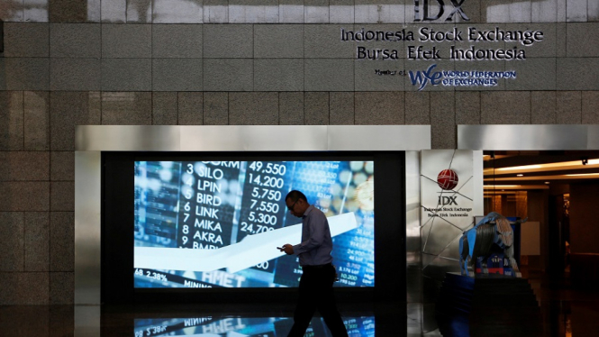 A man walks past screen at the Indonesia Stock Exchange building in Jakarta