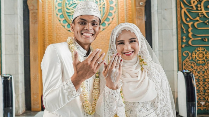 Bek Persebaya Rachmat Irianto bersama istrinya Siti Qonita memamerkan cincin perkawinan Minggu 1-11
