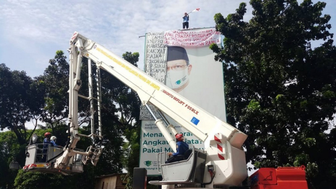 Seorang Pria Nekat Berdiri di Atas Papan Reklame Depan Mabes Polri