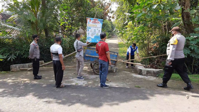 Sejumlah petugas satgas penanganan Covid-19 tingkat Kecamatan Simo sedang menutup aksen jalan dua dusun dengan bambu. ( Foto : Agus Saptono/ANTV)