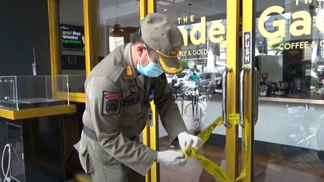 Seorang petugas satpol pp menyegel “ The Gade Coffe and Gold” di pusat kuliner Kota Tangerang di hari pertama pemberlakukan PPKM Darurat karena melanggar aturan