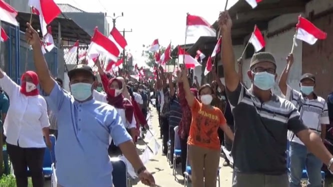 Sambil membawa bendera merah putih, Ratusan warga Desa Kosambi Timur, Kosambi, Tangerang, Banten, berjemur massal di bawah teriknya matahari dengan protokol kes