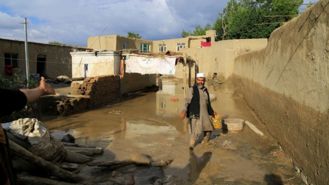 Seorang pria membersihkan rumahnya pasca banjir di Afghanistan.