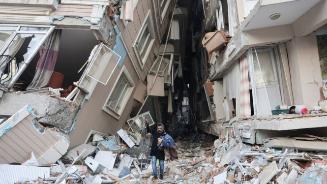 Seorang pria berjalan di antara bangunan runtuh akibat gempa Turki.