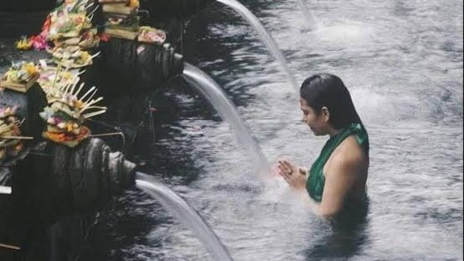 Seorang wanita sedang melakukan ritual melukat