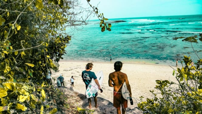 Wisatawan akan berselancar di pantai Bali