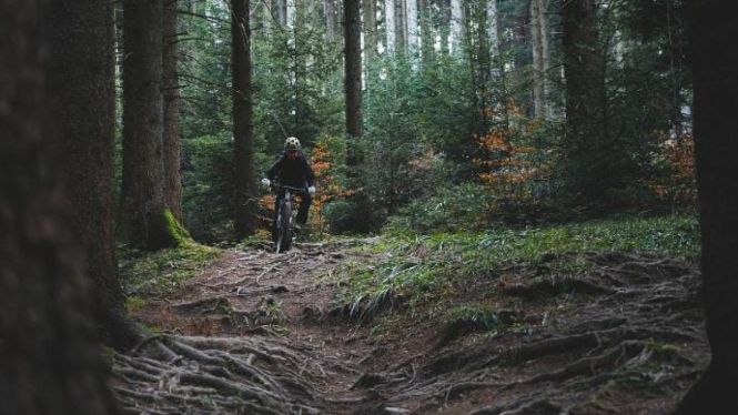 Seorang pendaki berpose dengan sepeda di puncak Gunung Agung