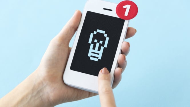 Close-up tangan memegang smartphone.
