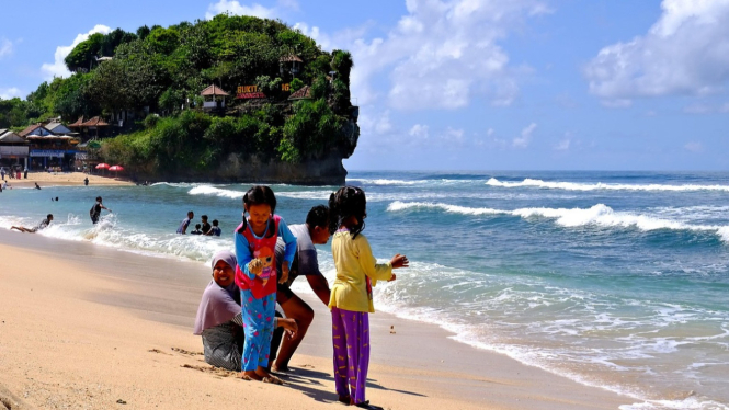 Keluarga berkunjung ke pantai saat liburan panjang