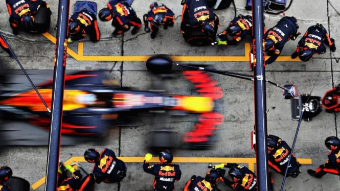 Mekanik F1 mengganti ban dan mengisi bahan bakar mobil di pit stop.