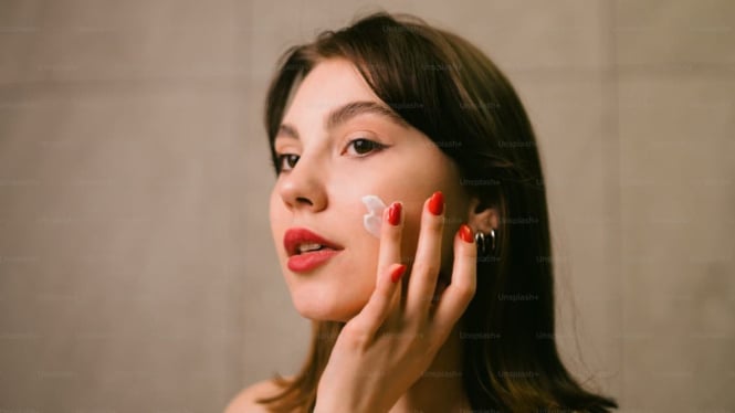 Perempuan memakai cream pemutih wajah