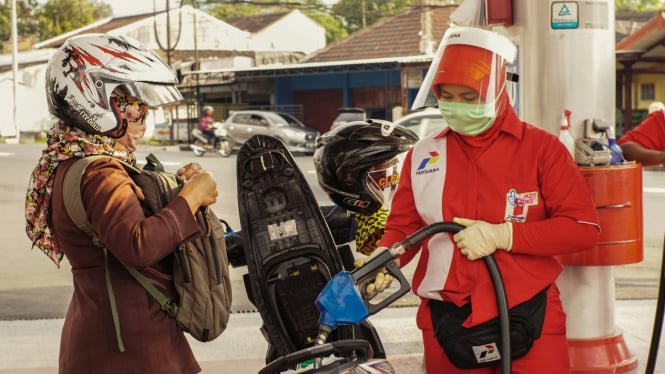 Petugas SPBU melayani pengendara motor