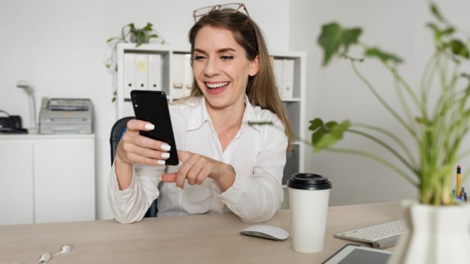 Wanita mengecek smartphonenya saat bekerja