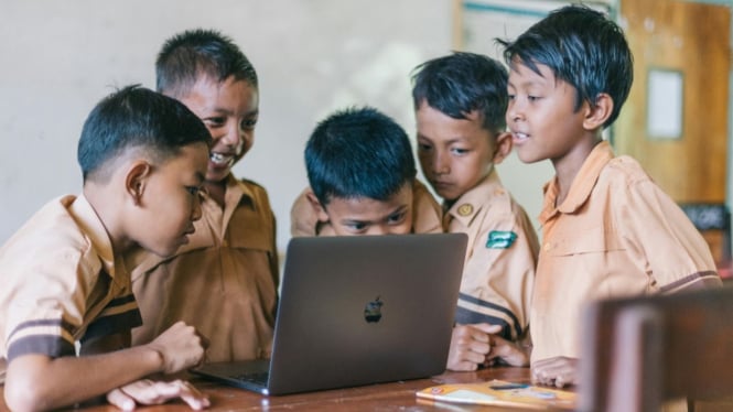 Anak-anak sedang belajar menggunakan laptop.