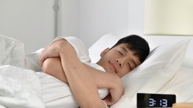 Seorang pria beristirahat di tempat tidur dengan nyaman