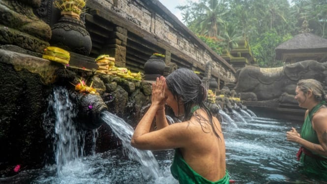 Seorang wanita sedang melukat di Pura Tirta Empul