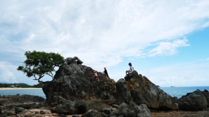 Wisatawan sedang bermain di bebatuan yang ada di pantai