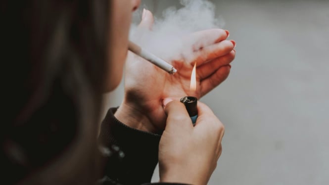 Ilustrasi wanita saat menyalakan sebuah rokok.