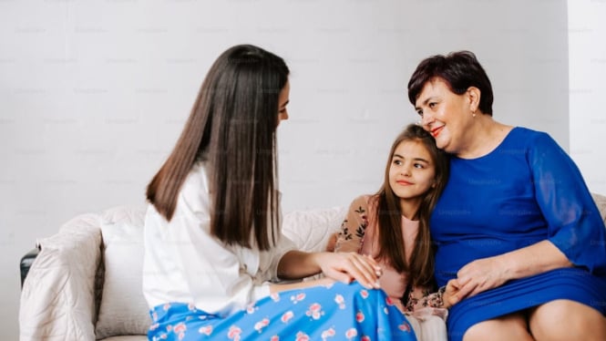 Menantu, mertua dan cucunya sedang duduk di sofa bersama