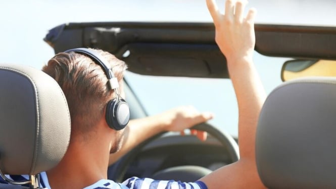 Seorang pria yang mengemudi sambil mendengarkan music