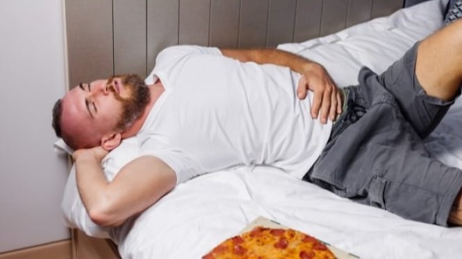 Seorang pria yang tidur setalah makan pizza
