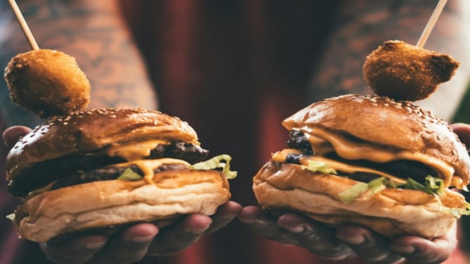 Ilustrasi seseorang yang sedang memegang dua hamburgers.