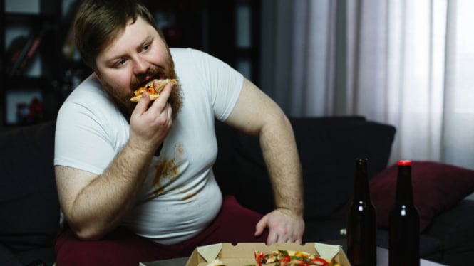 Pria gemuk yang sedang menukmati pizza dengan lahap
