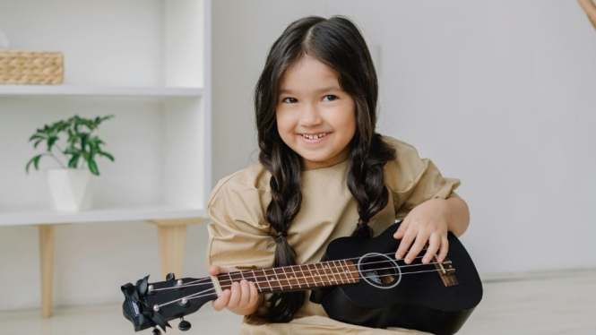 Ilustrasi seorang anak yang sedang bermain ukulele.