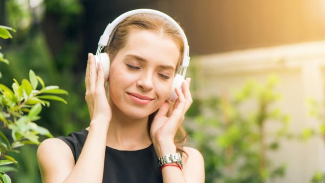 Ilustrasi seorang wanita sedang memakai headphone.