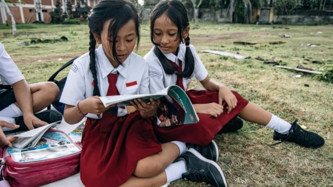 Seorang anak Indonesia fokus membaca buku