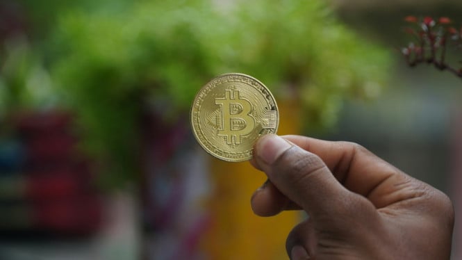 Sesorang sedang memegang aset Bitcoin