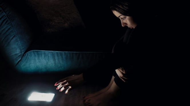 Ilustrasi seorang wanita yang menunda tidur untuk bermain handphone.