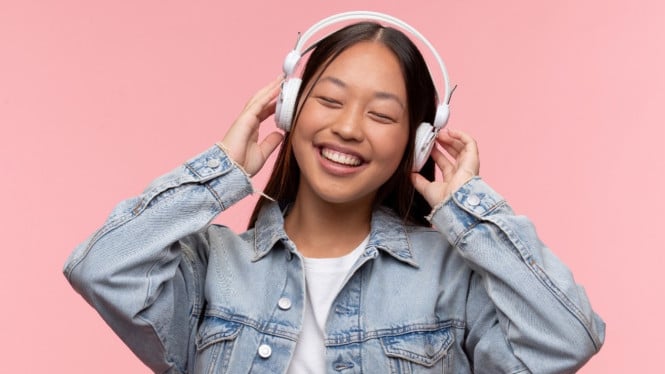 Seorang remaja tengah asik mendengarkan headset