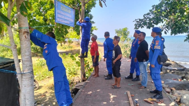 Petugas Satpolairud Memasang Papan Himbauan di Pantai Rening