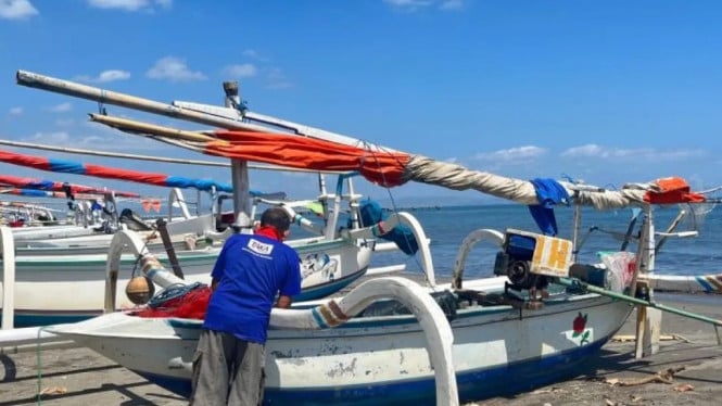 Seorang nelayan nampak mempersiapkan perahu sebelum berlayar