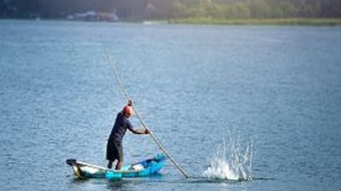 Seorang nelayan sedang menangkap ikan di danau Toba