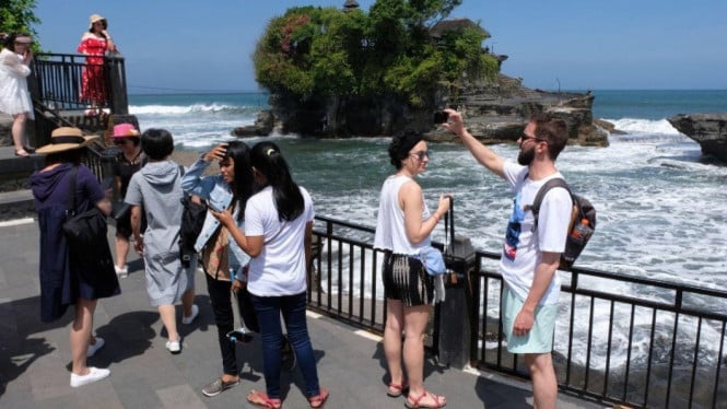 Wisatawan Asing sedang menikmati keindahan pantai Bali.