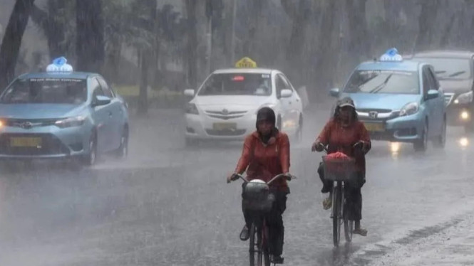 Masyarakat terkena hujan deras di jalan