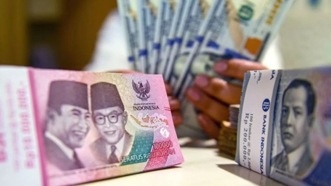 Petugas menunjukan uang pecahan dolar AS dan rupiah