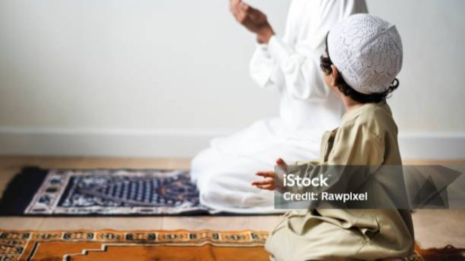 Seorang anak tengah berdoa bersama bapaknya di bulan Ramadhan