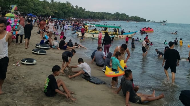 Wisatawan Bermain Air di Pantai.