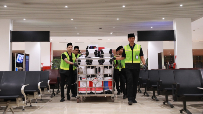 Petugas saat mengangkut koper haji di bandara