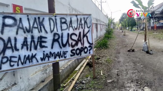 Spanduk protes warga Desa Sumberberas di jalan rusak