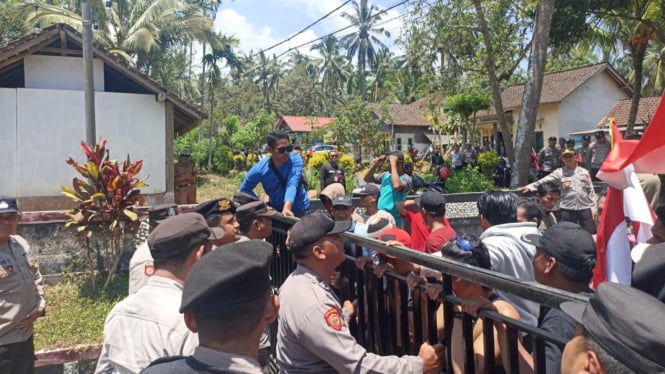 Massa berusaha menerobos barikade polisi untuk masuk ke kantor desa