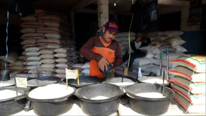 Pedagang sedang menakar beras untuk pembeli