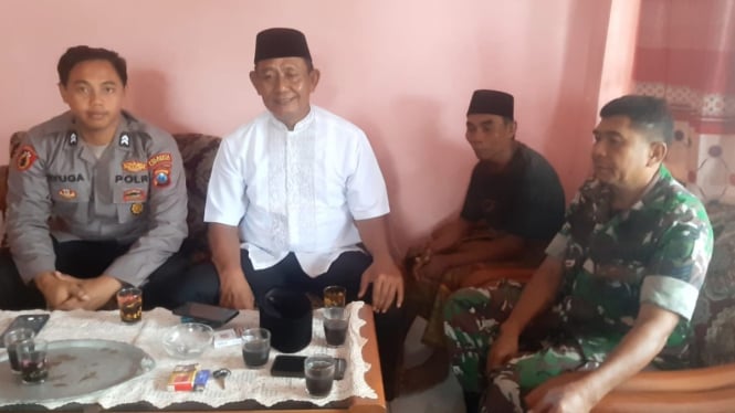 Kusni (tengah) bersama aparat keamanan dan Kades Abu Bakar